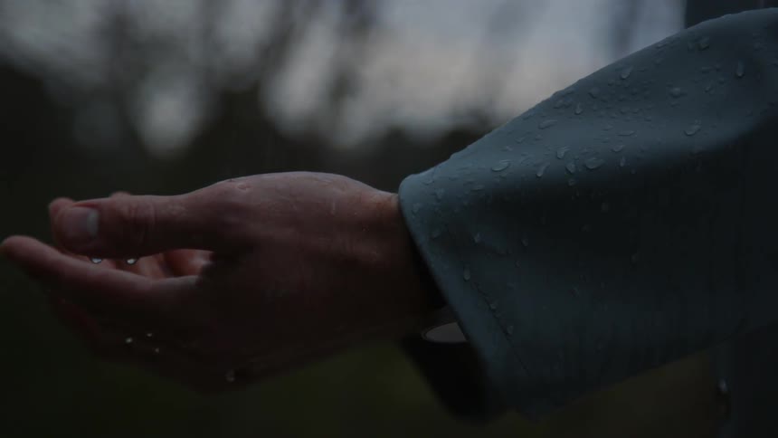 Someone is standing in the rain and catching it in their hands
