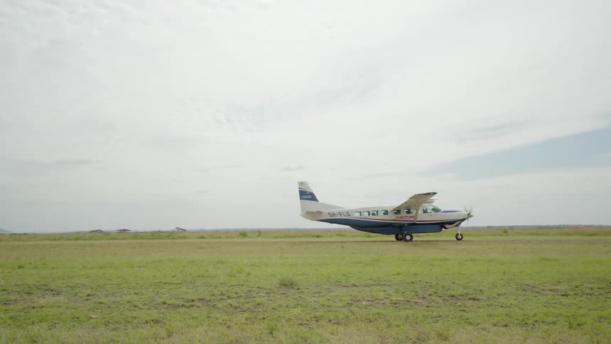 A small plane is landing on a green field