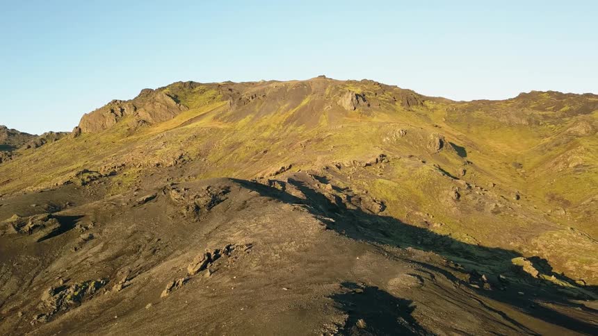 A rocky mountainside is shown on a clear day in iceland