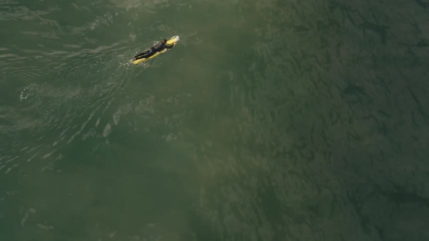 A surfer is paddling out beyond the waves during the day