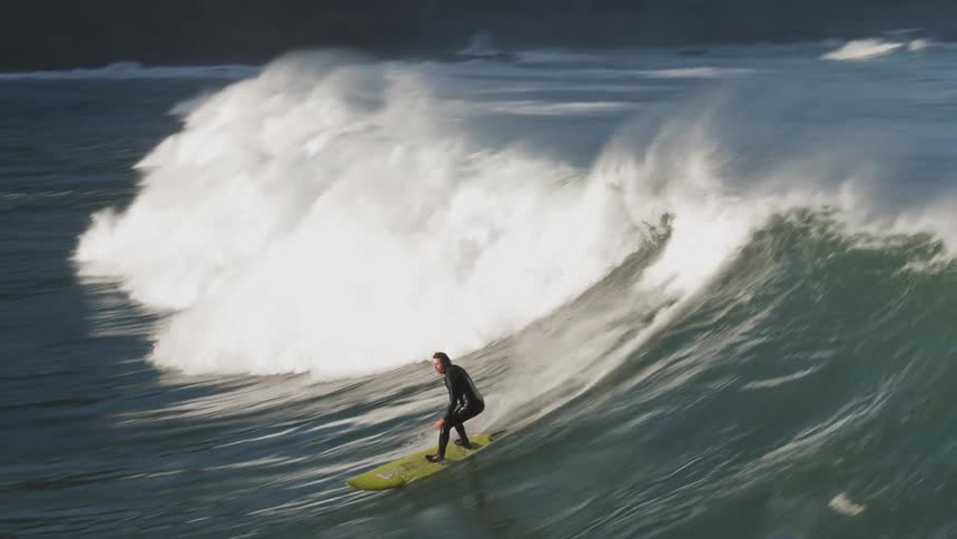 A surfer catches and rides a wave during the day
