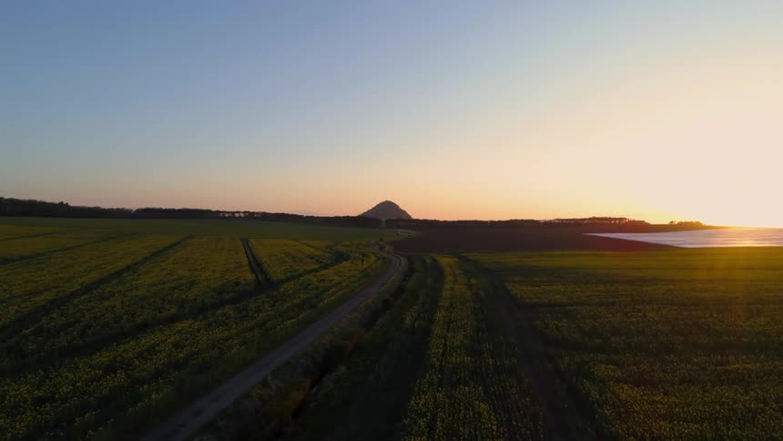 The fields are green and the sun is setting
