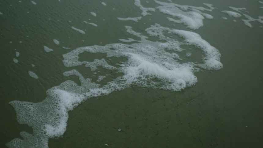 Foam ripples flow onto the shoreline on the beach
