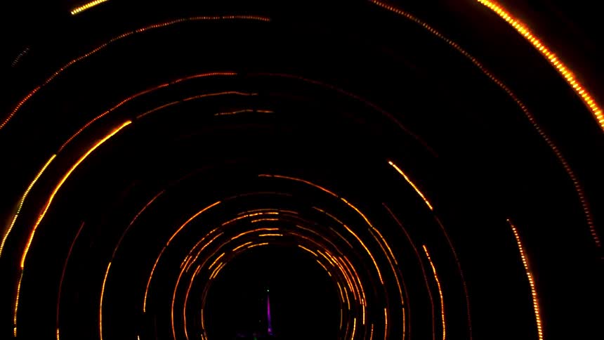 Someone is walking through a tube of laser lights that are swirling around them