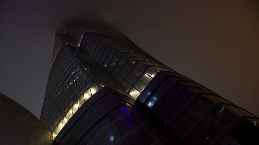 Neon green light shoots up the face of a skyscraper