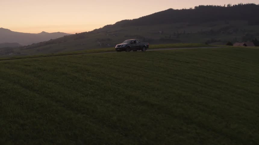 A truck is sitting on top of a ridge line at sunset