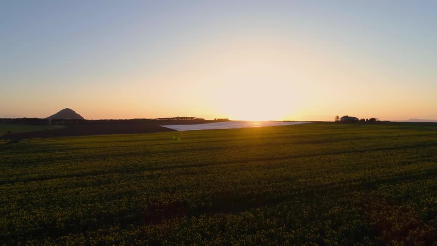 The sun sets over a rural field on a clear day