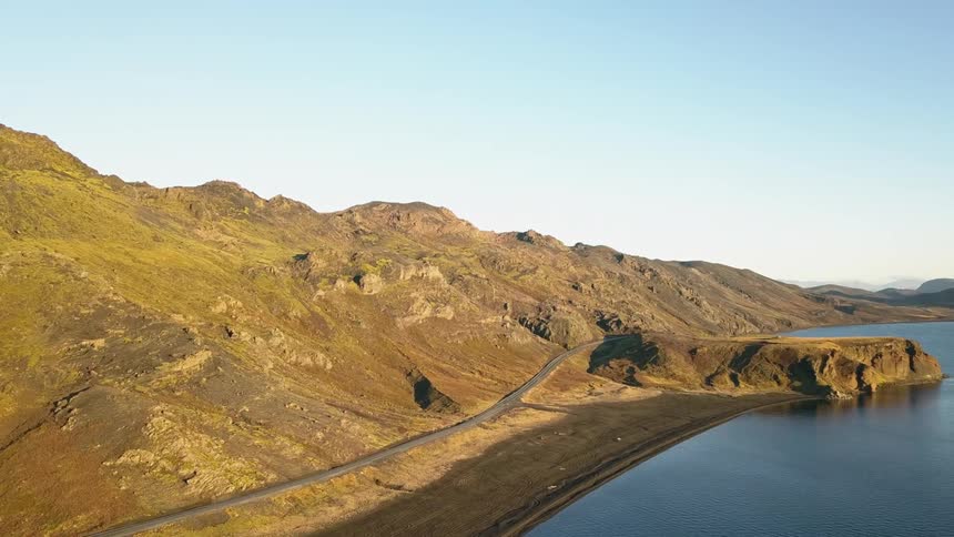 A road cuts along the base of a hill next to lake Kleifarvatn in Iceland