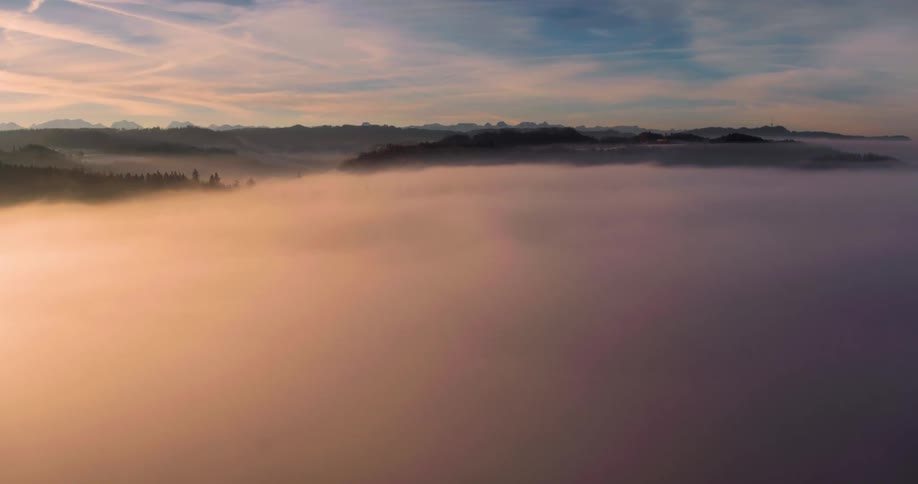 The sun sets in the mountains on a misty day