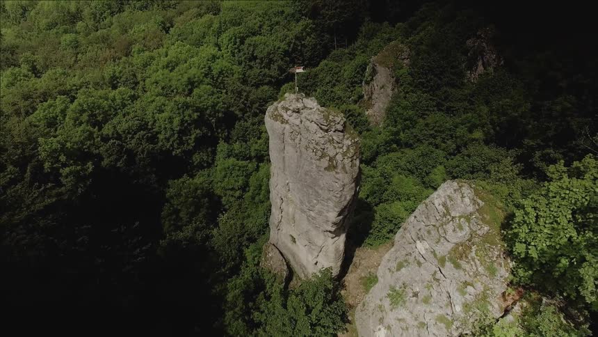 A large cliff is being filmed from a drone