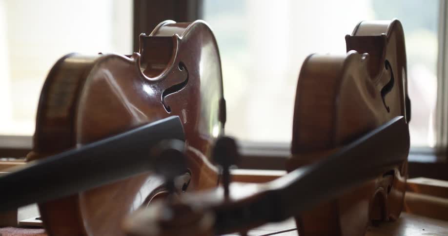 Two violins on their sides next to a window