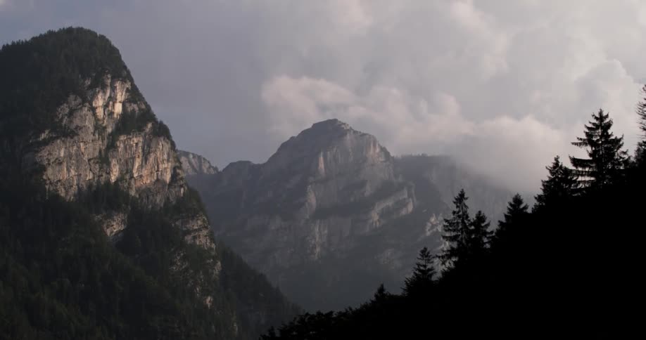 The mountains are high and surrounded by large clouds