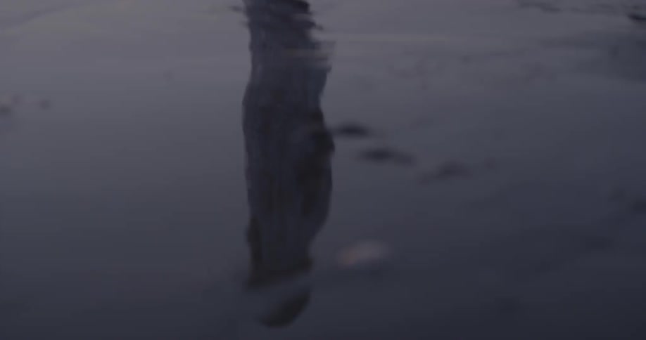 A person walks on a sandy beach at sunset