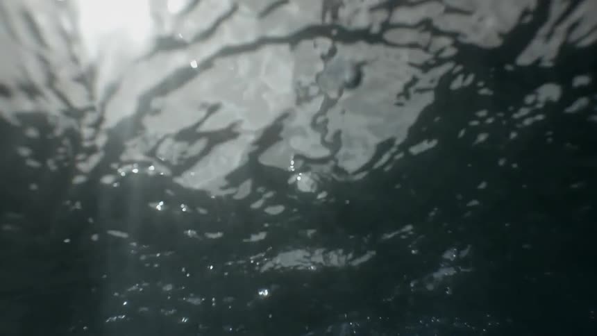 An oar cuts the water and stirs bubbles beneath the ocean's surface