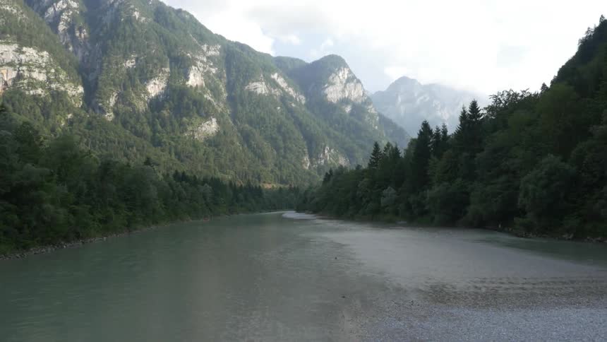 Water flows in a river between wooded shorelines