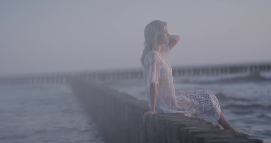 Woman sits on a wooden ledge in the water