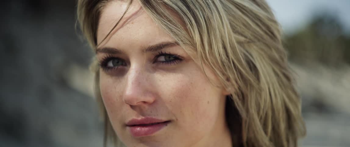 A blonde haired woman stands outside in the wind