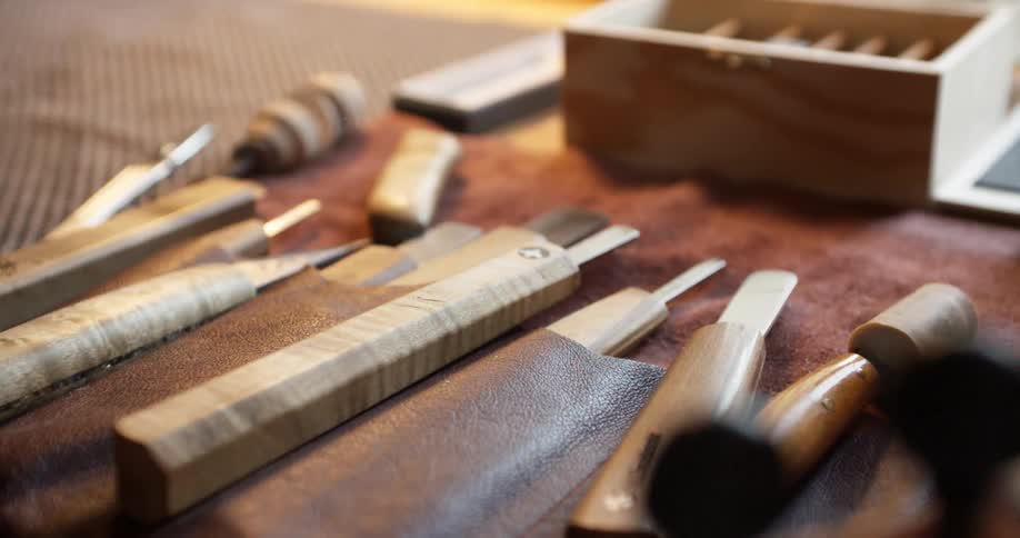 A man arranges tools on a table next to a violin