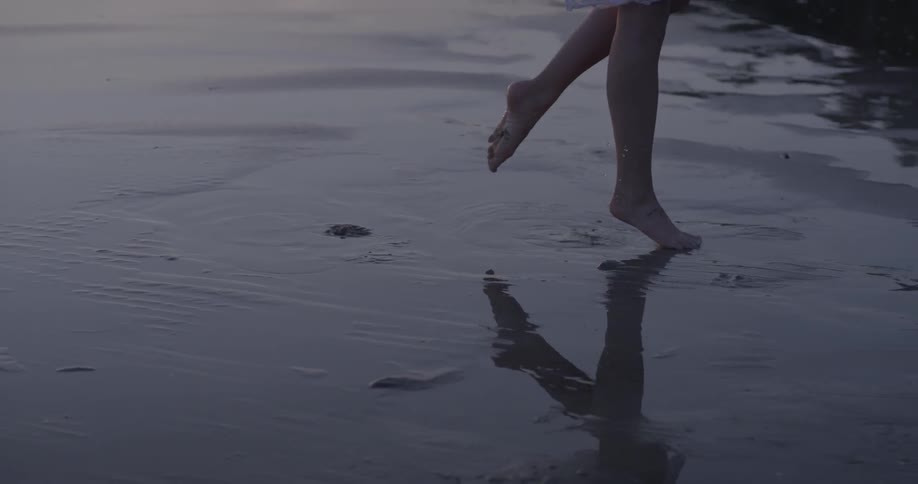 A woman in white is walking on a beach and jumping