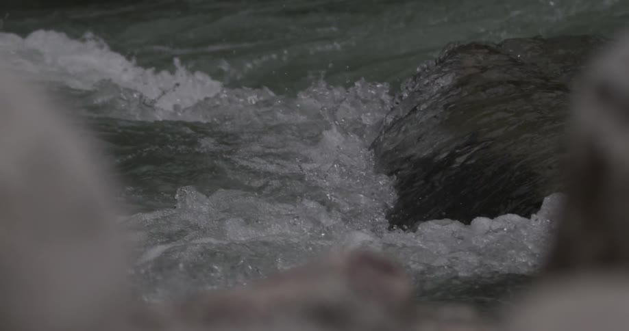 Water splashing off a small rock into a river