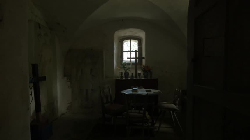 A dark room with a table and cross in it