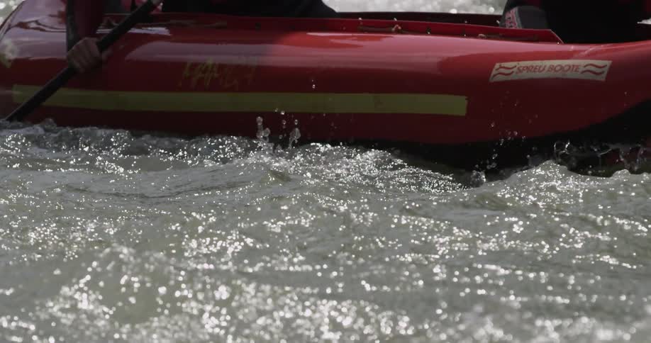 A kayak with two people is navigating through some choppy water