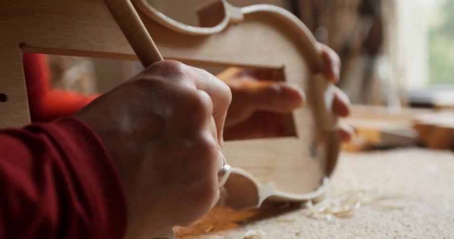 A man is carving a violin