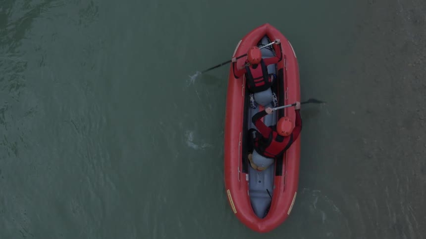 A drone is filming some river rafters from above in calm water