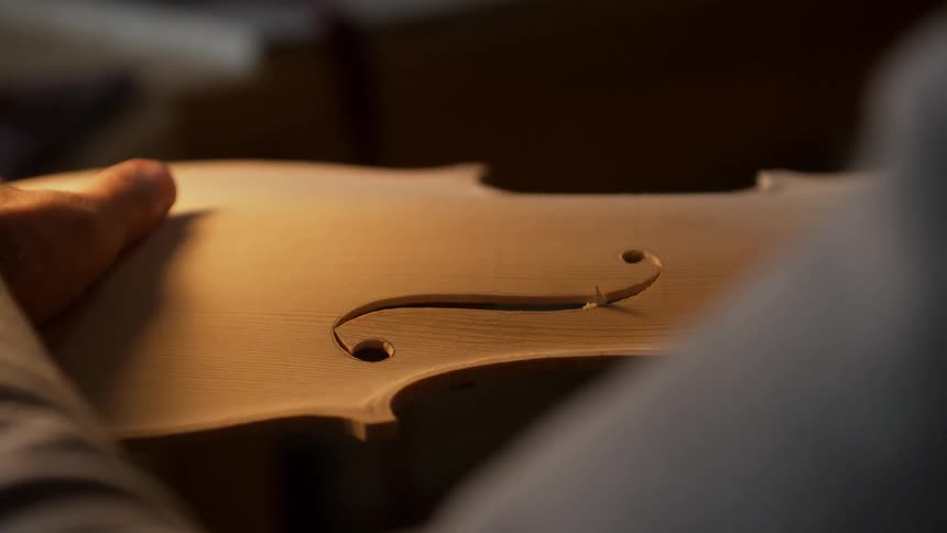 A man is carving a violin