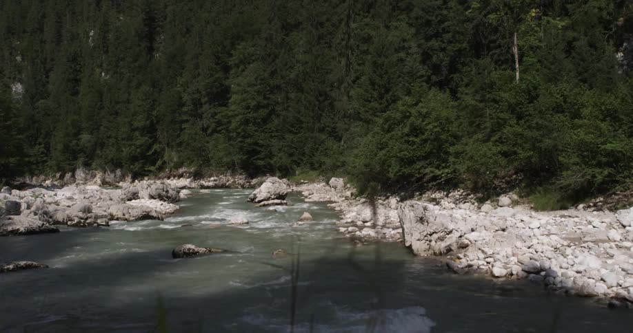 A person walking to the edge of a cliff overlooking a stream