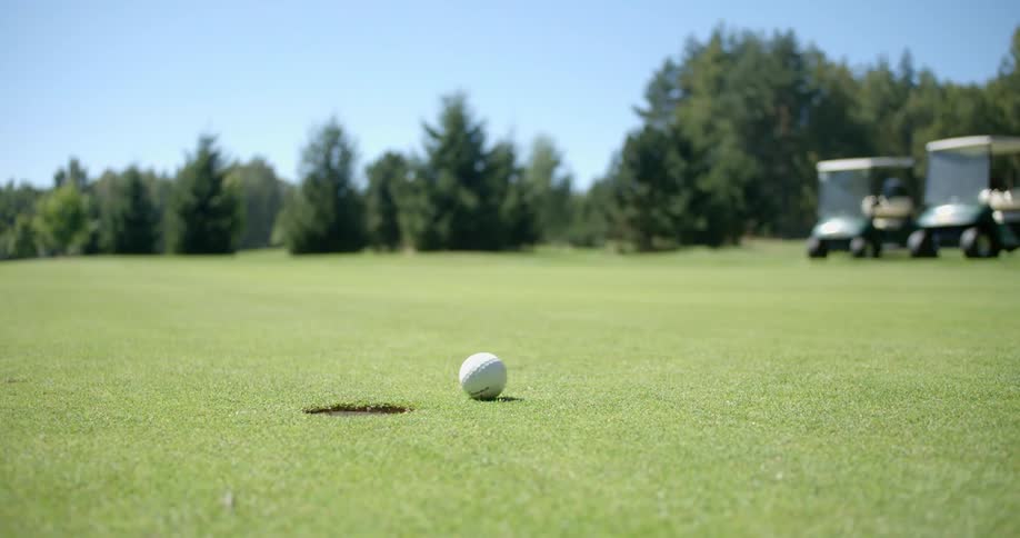 A golf ball rolls into the hole