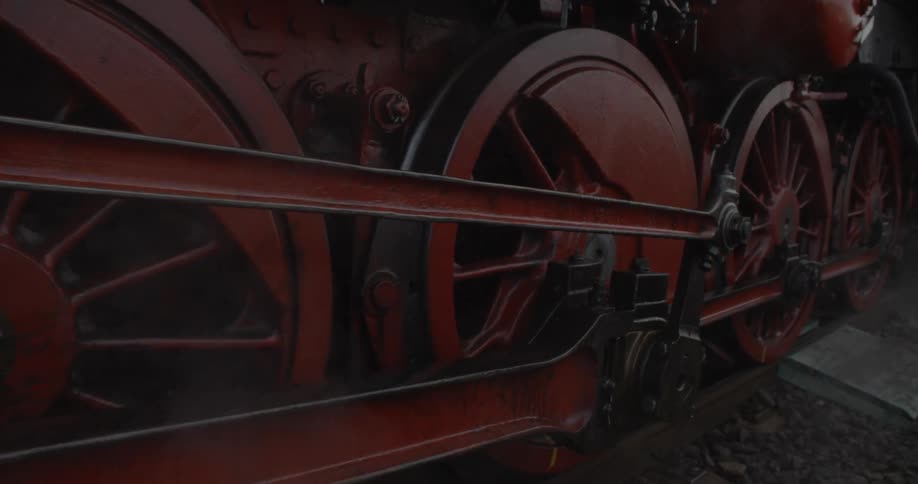 A steam train begins to roll down a track during the day