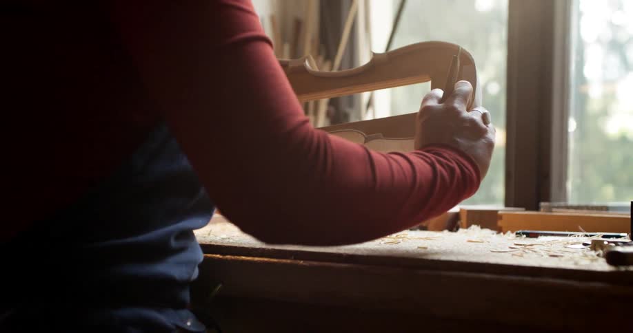 A person makes a violin at a workbench