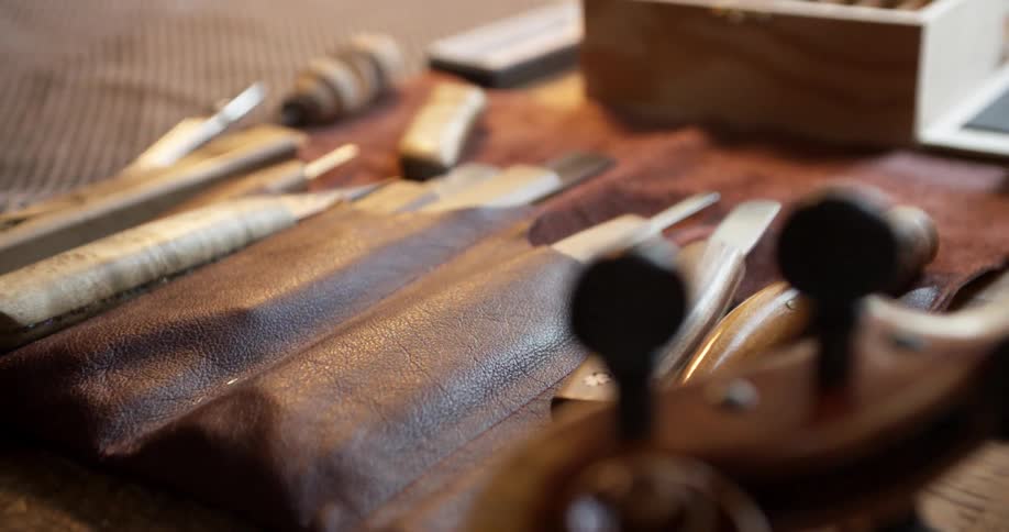 Someone picks up a chisel from a wood carving set