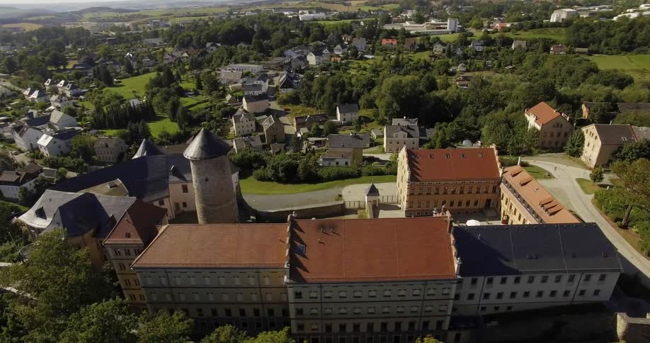 A drone is flying over an old school on a hill