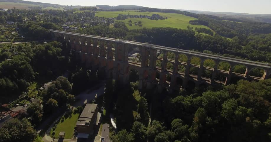 A roman aqueduct hovers over a river valley