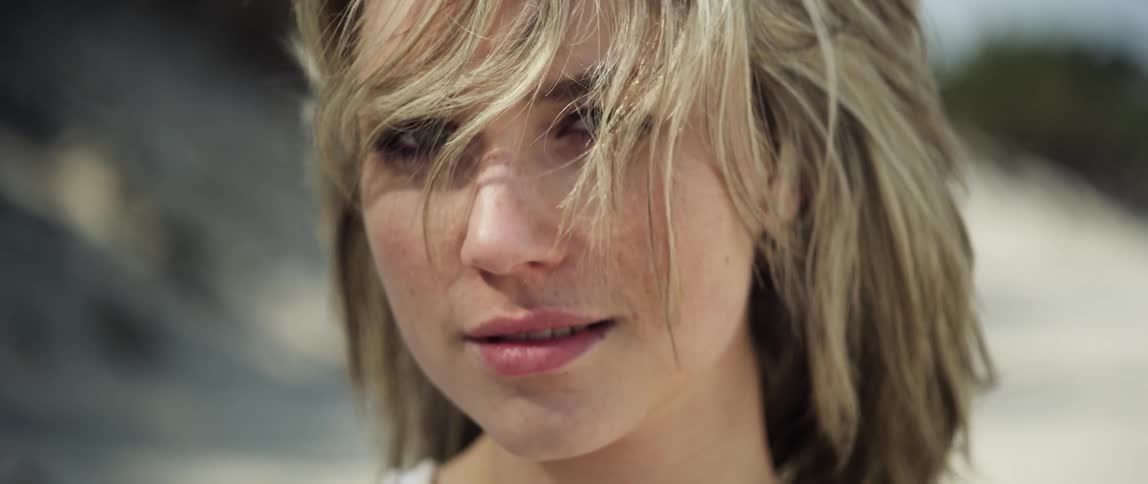 A woman is smiling outside on a windy day