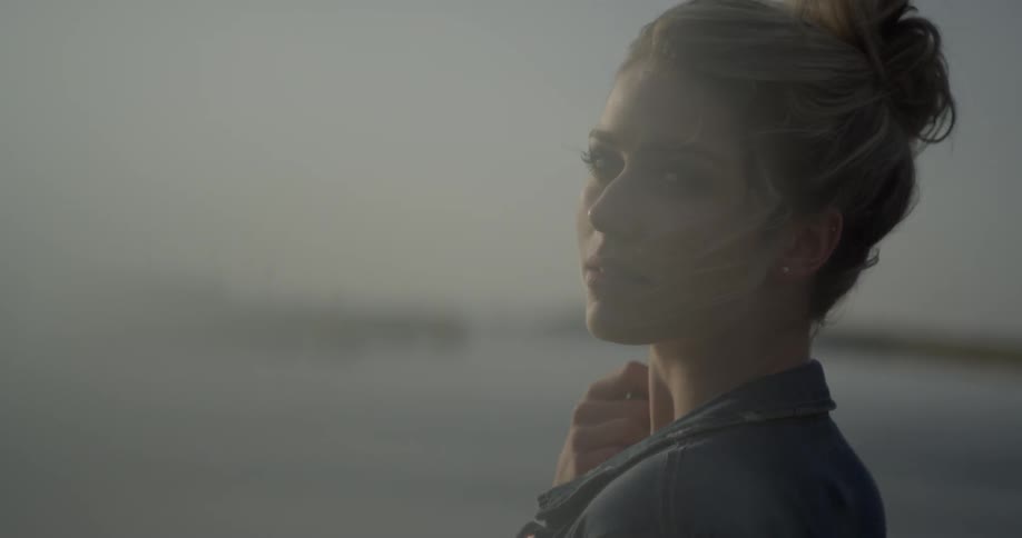 A woman by the shore brushes her hair