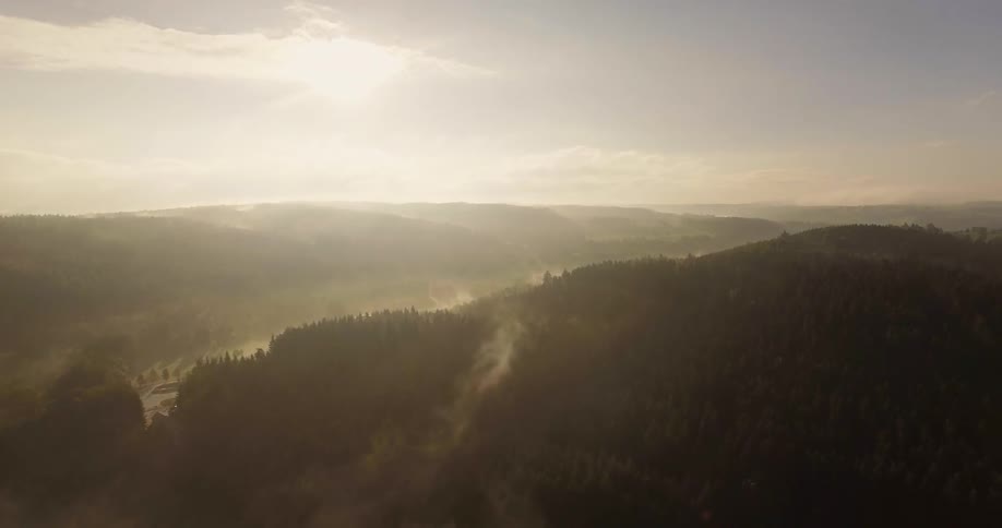 The mountains below are green and covered with fog