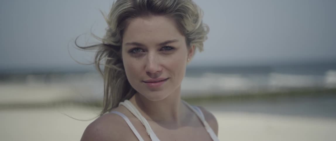 A girl is smiling at the camera on the beach