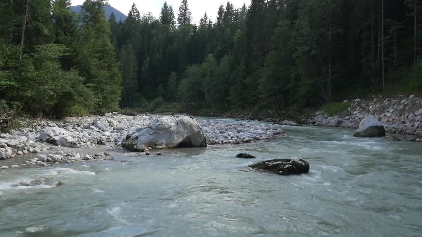 A creek flows around the stony shoreline