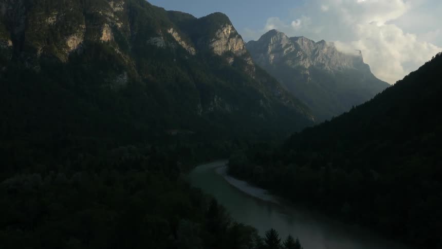 Shadows cover a river valley in a mountain range during the day