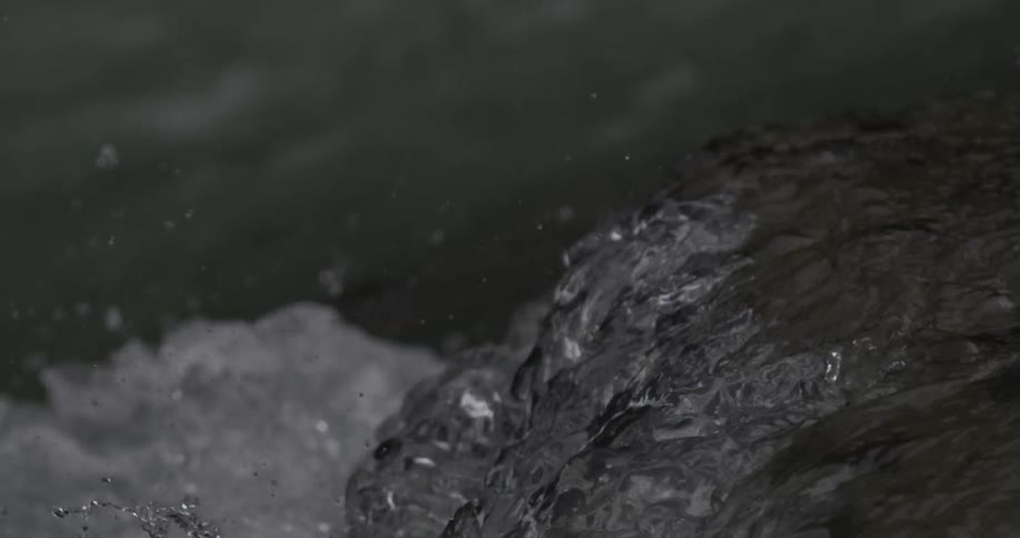 Water flows over a rock in a rushing river