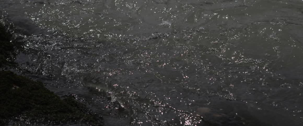Water splashes and laps against a shoreline during the day