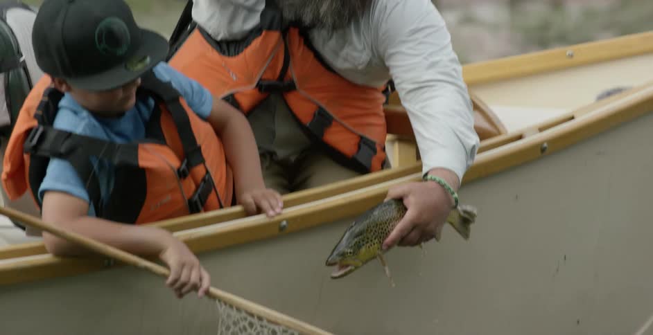 A man is removing a hook from a fish and placing it in a net
