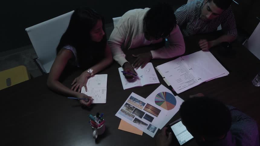 A group of people are studying graphs and charts at a conference table