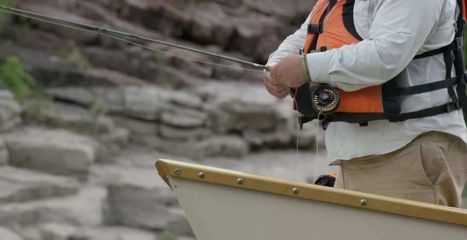A man is standing on a boat and fishing