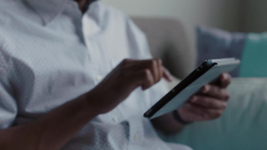 A man is using a tablet on the couch