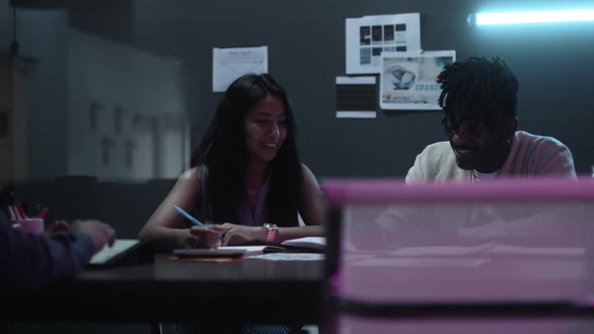Workers in an office sit at a table and converse