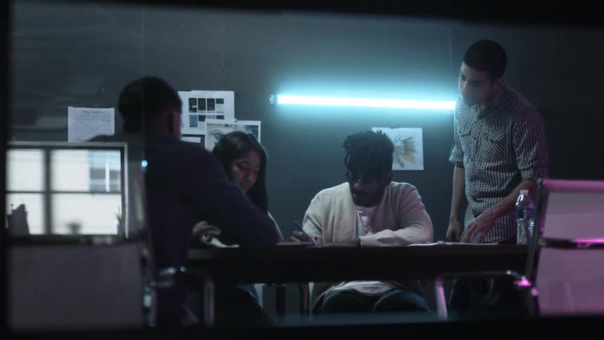 People sit and stand around a table talking